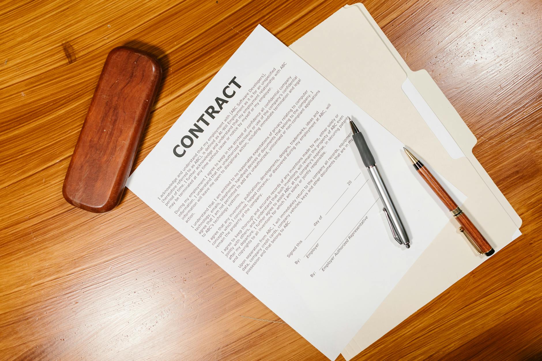 High-angle view of a contract document with pens on a wooden table
