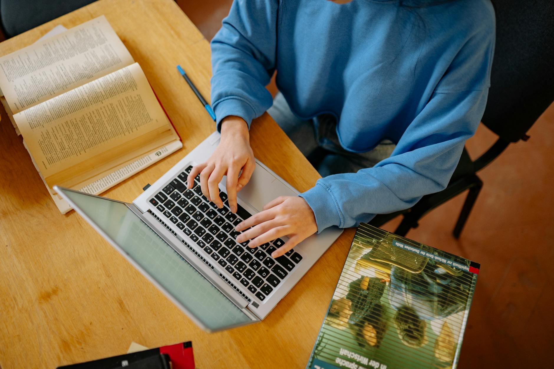 A person studying at a desk with a laptop and notes